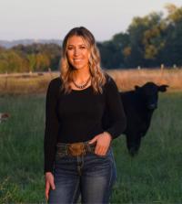 Marissa Fisher standing in front of a cow